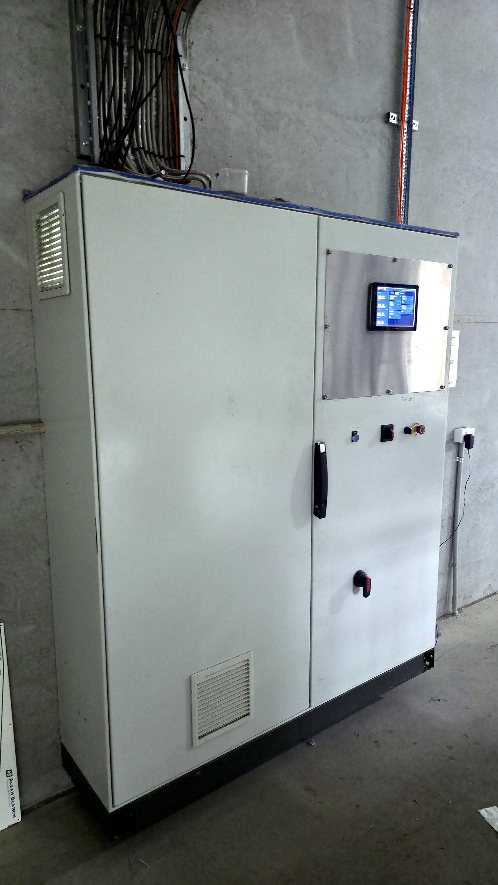 Finished dryer control cabinet on site — touchscreen HMI and emergency stop on the door